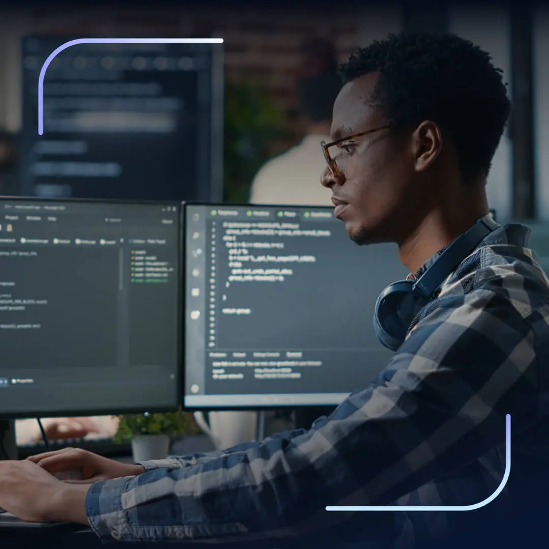 Developer working at dual monitors with code displayed on screen.