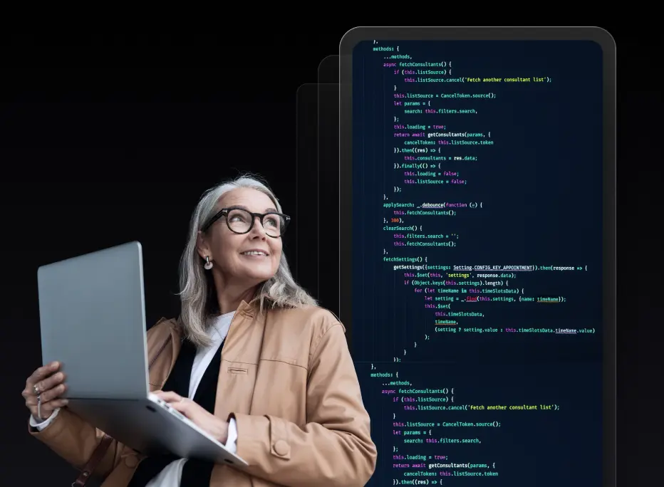 A smiling older woman with gray hair and glasses holds an open laptop while looking upward. Behind her is an enlarged digital screen displaying colorful lines of programming code on a dark background.
