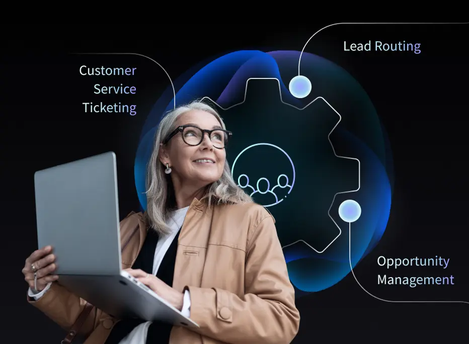 A middle-aged woman with gray hair and glasses holds an open laptop and smiles while looking upward. Behind her is a glowing abstract graphic of a gear and user icons. Text callouts around the graphic read “Customer Service Ticketing,” “Lead Routing,” and “Opportunity Management,” illustrating CRM-related features.