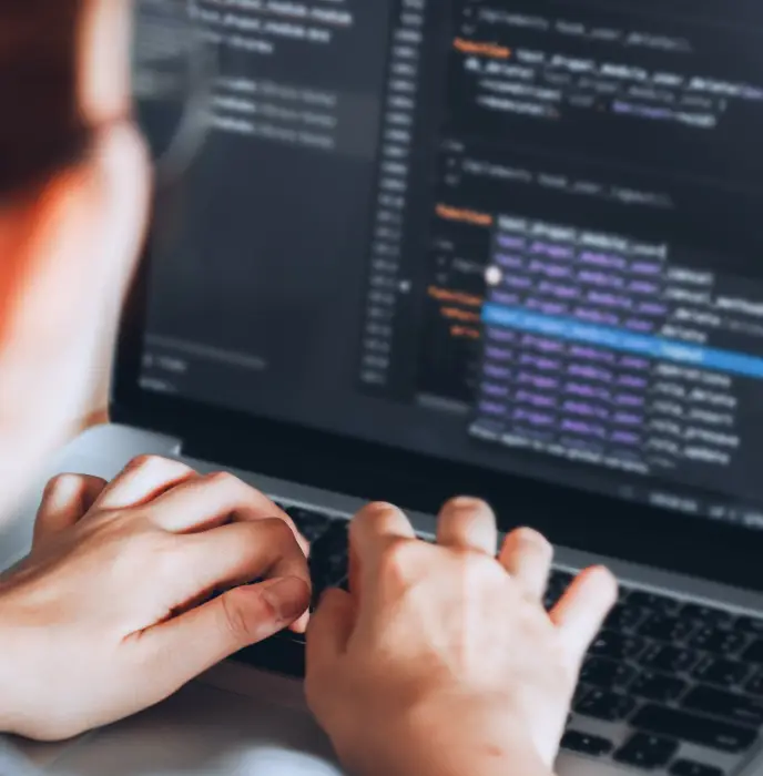 <p data-start="55" data-end="162">Close-up view of a person typing on a laptop, with lines of code displayed on the screen.</p>