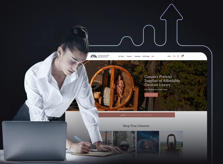 A woman in a white blouse leans over a desk while writing in a notebook, with an open laptop beside her. Behind her is a large, stylized graphic of a website featuring an outdoor luxury product—a wooden hot-tub–style structure with a person seated inside. The background includes a dark, glowing outline of an upward-pointing arrow, suggesting growth or progress.