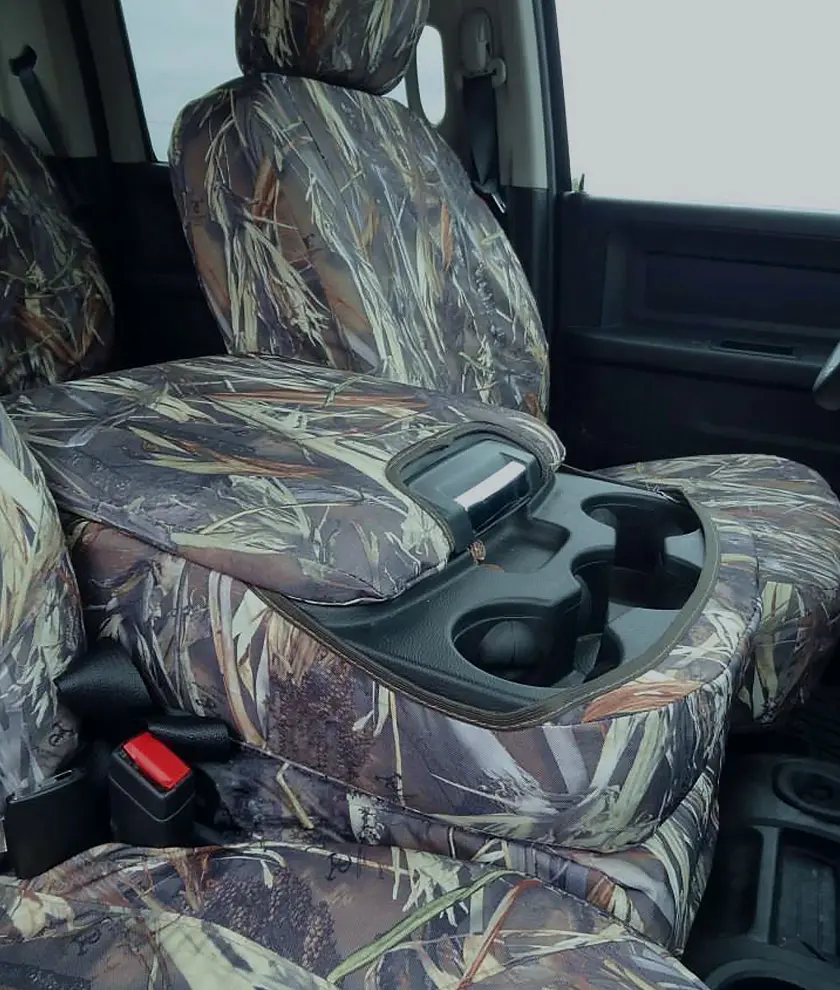 Close-up of a vehicle’s front interior with camo-pattern Durafit seat covers, showcasing a precise fit around the seats and center console with integrated cup holders, emphasizing durability and rugged styling.