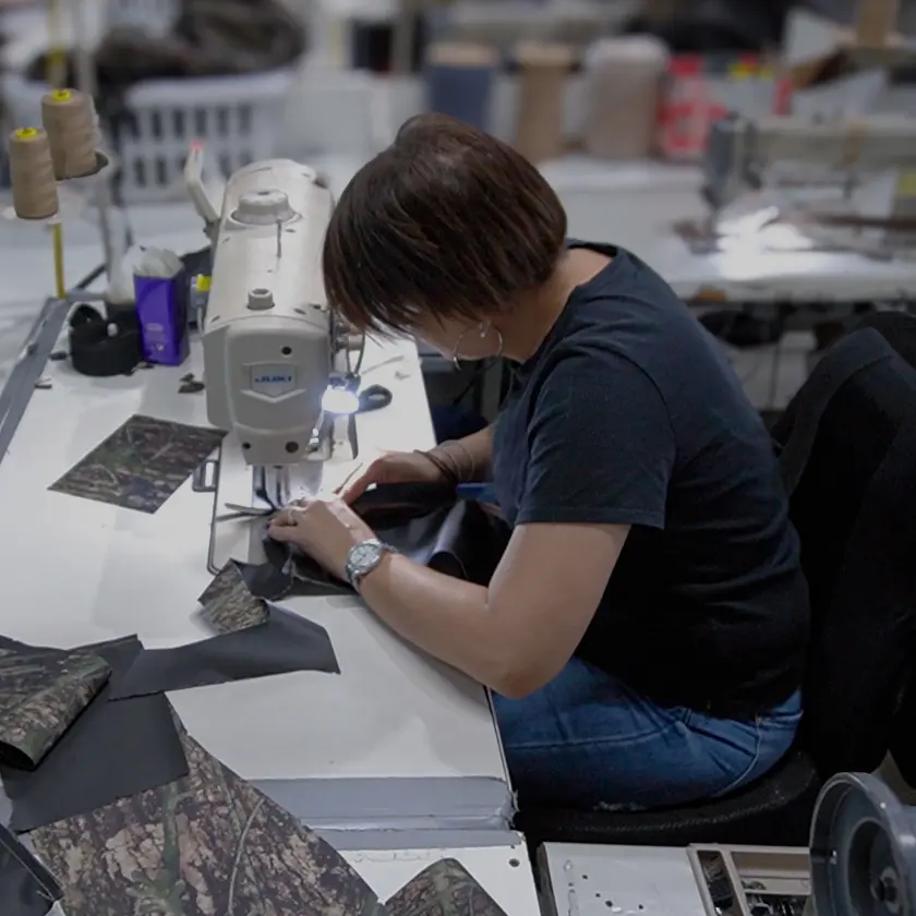 Close-up of a worker sewing Durafit seat cover materials, highlighting hands-on craftsmanship and attention to detail in the manufacturing process.