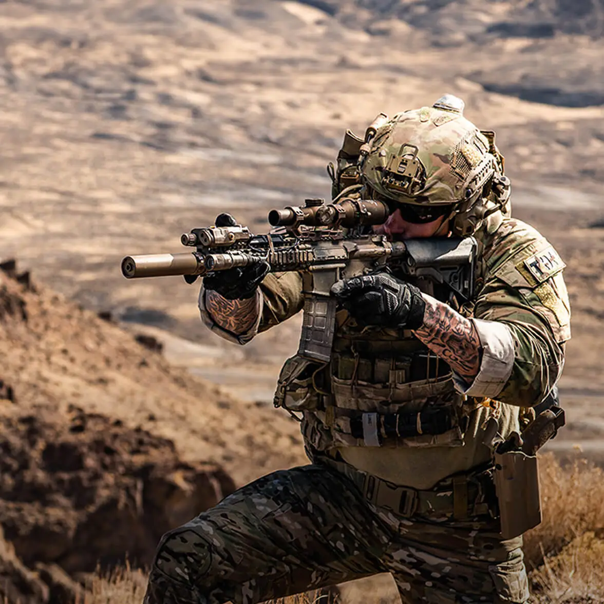 Man kneeling in tactical gear holding a firearm