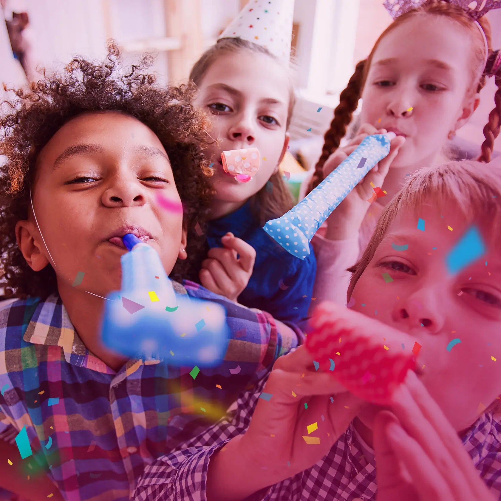 Children celebrating with party horns and confetti at a birthday party.