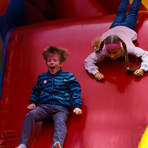 Children playing on a colorful inflatable slide at a party rental event.
